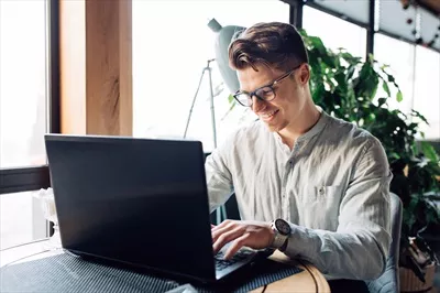 عکس مرد عینکی در حال کار با لبتاب