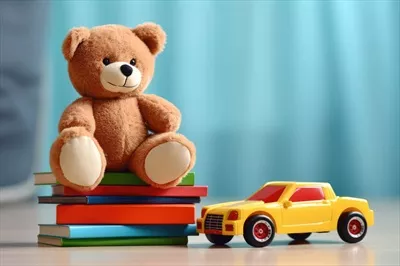 عکس عروسک خرس نشسته روی کتاب ها و ماشین اسباب بازی در اتاق کودک