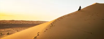 عکس گام های تنهایی بر روی تپه های شنی در غروب کویر