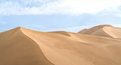 عکس مناظر زیبای تپه های شنی در زیر آسمان آبی و ابری