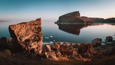 عکس زیبای سنگ های بزرگ در دریاچه ارومیه با کوه ها و آسمان آبی