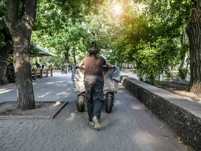 عکس مردی که در حال هل دادن یک کالسکه در مقابل خود است