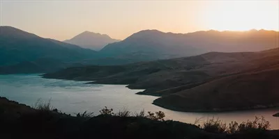 عکس غروب آفتاب بر فراز کوه ها و دریاچه ای آرام و زیبا