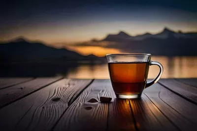 عکس یک فنجان چای روی میز چوبی با پس زمینه کوه های زیبا و دلنشین