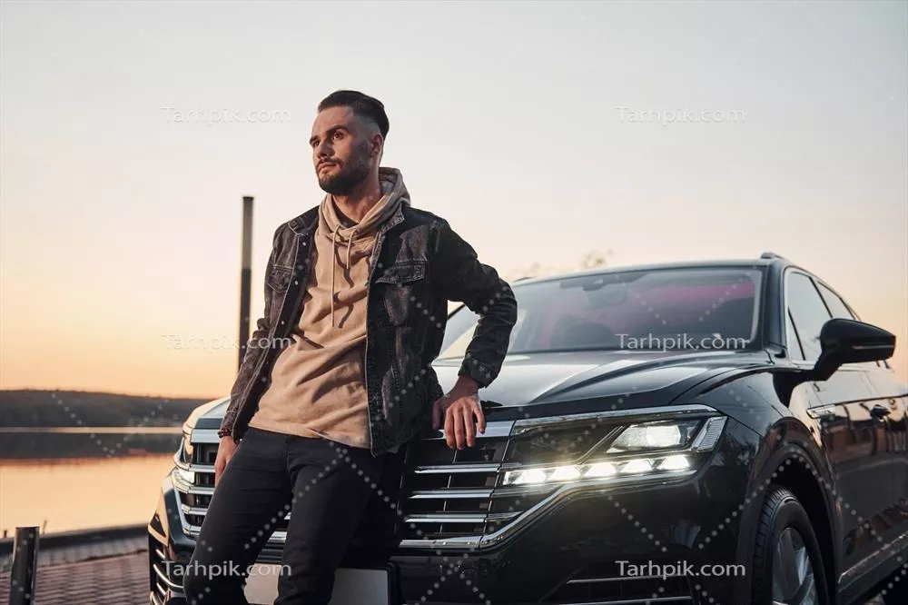 عکس مردی جذاب و با استایل در لباس های مد روز، تکیه زده بر خودروی مشکی اش