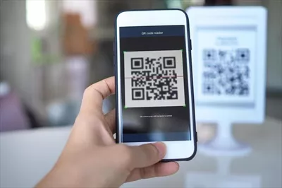 عکس زنان با استفاده از اپلیکیشن موبایل، کدهای QR را در فروشگاه ها اسکن می کنند