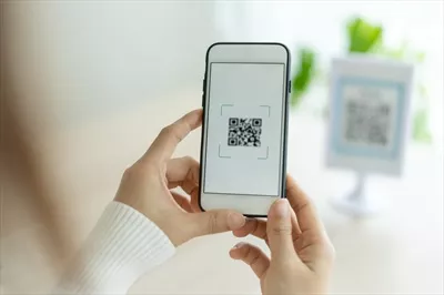 عکس زنی مدرن که با استفاده از تلفن همراه خود بارکد یا کد QR را اسکن می کند