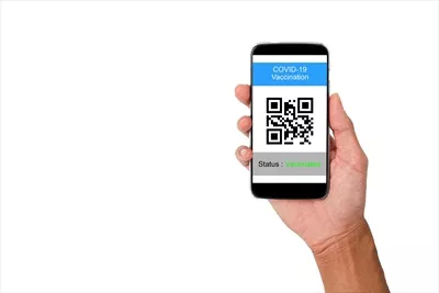 عکس نشان دادن وضعیت واکسیناسیون علیه کووید-19 با موبایل در دست