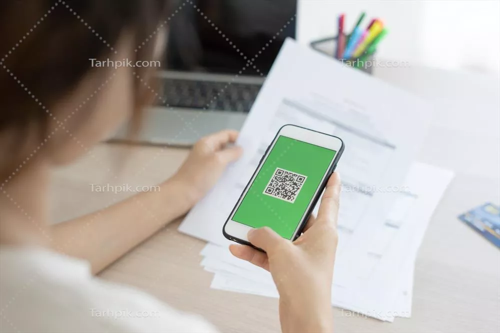 عکس زنی که با استفاده از تلفن همراه خود بارکد یا کد QR را اسکن می کند تا قبض کارت اعتباری خود را پرداخت کند