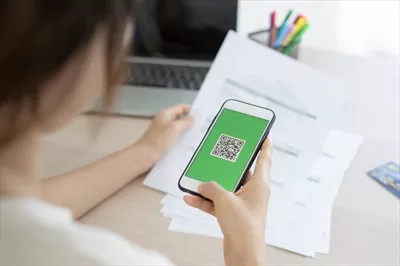 عکس زنی که با استفاده از تلفن همراه خود بارکد یا کد QR را اسکن می کند تا قبض کارت اعتباری خود را پرداخت کند