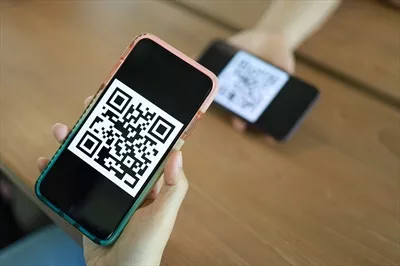 عکس زنی در حال اسکن کد QR برای خرید آنلاین با استفاده از فناوری بدون پول