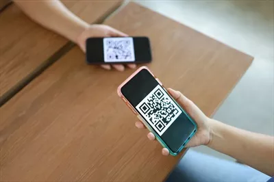 عکس زنی که در حال اسکن کد QR برای خرید آنلاین با فناوری بدون پول است