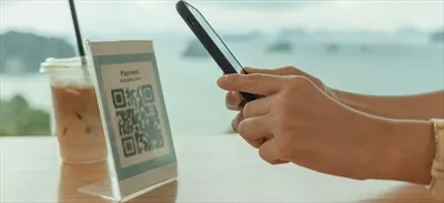 عکس زنی مدرن که با استفاده از تلفن همراه خود بارکد یا کد QR را اسکن می کند تا صورتحساب کارت اعتباری خود را پرداخت کند