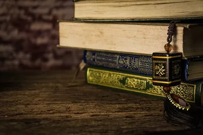 عکس حضرت محمد (ص) و قرآن کریم: نماد ایمان و فرهنگ اسلامی بر روی میز