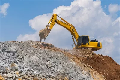عکس عملیات حفاری با بیل مکانیکی در فضای باز زیر آسمان آبی