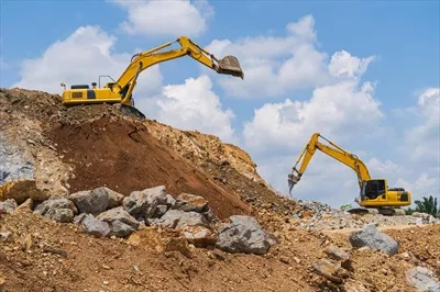 عکس عملیات حفاری با بیل مکانیکی در فضای باز زیر آسمان آبی