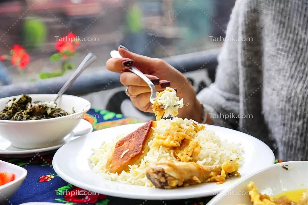 عکس زنی که در حال لذت بردن از یک وعده غذایی در کنار میز است