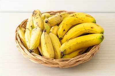 عکس موزهای تازه و زرد در سبدی زیبا بر روی میز چیده شده اند