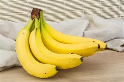 عکس موز تازه بر روی یک تخته چوبی، نمایی زیبا و طبیعی