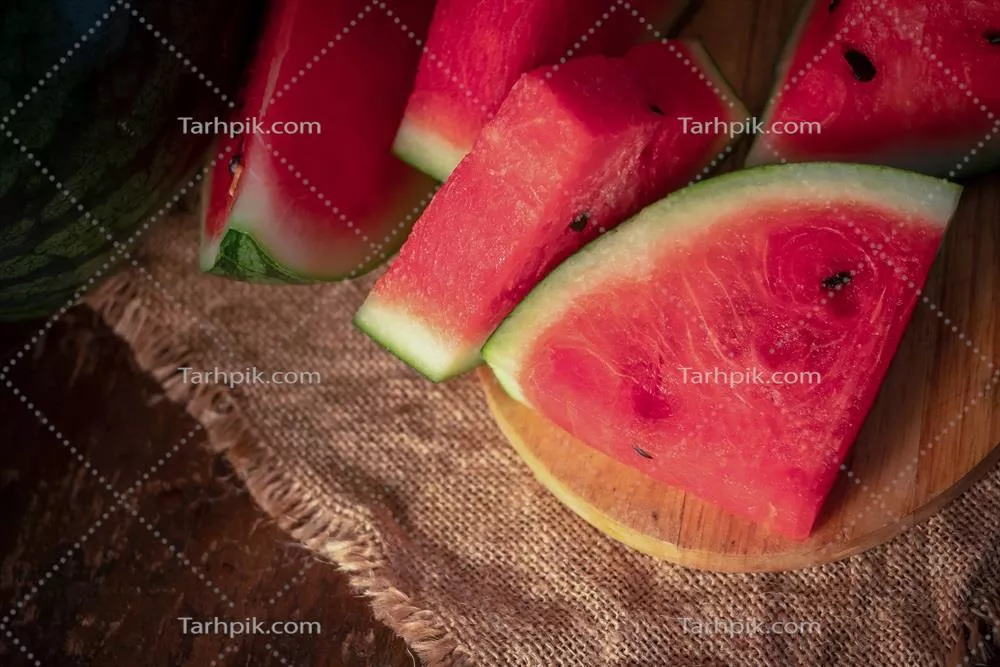 عکس تکه های هندوانه تازه و خوشمزه در پس زمینه چوبی طبیعی