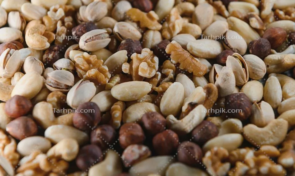 عکس مخلوطی از آجیل های خوشمزه در کاسه چوبی بر روی میز چوبی