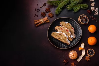 عکس دسر سنتی کریسمس: استولن با مارزیپان، توت و آجیل در پس زمینه تیره