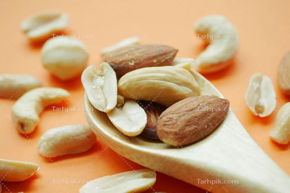 عکس ترکیب خوشمزه بادام و فندق در قاشق چوبی - تصویری از طبیعت
