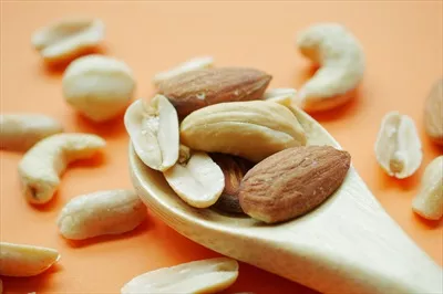 عکس ترکیب خوشمزه بادام و فندق در قاشق چوبی - تصویری از طبیعت
