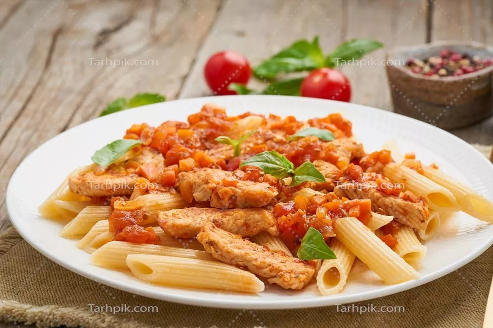عکس پاستا پنه با فیله مرغ یا بوقلمون و سس گوجه فرنگی بر روی چوب کهنه