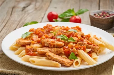عکس پاستا پنه با فیله مرغ یا بوقلمون و سس گوجه فرنگی بر روی چوب کهنه