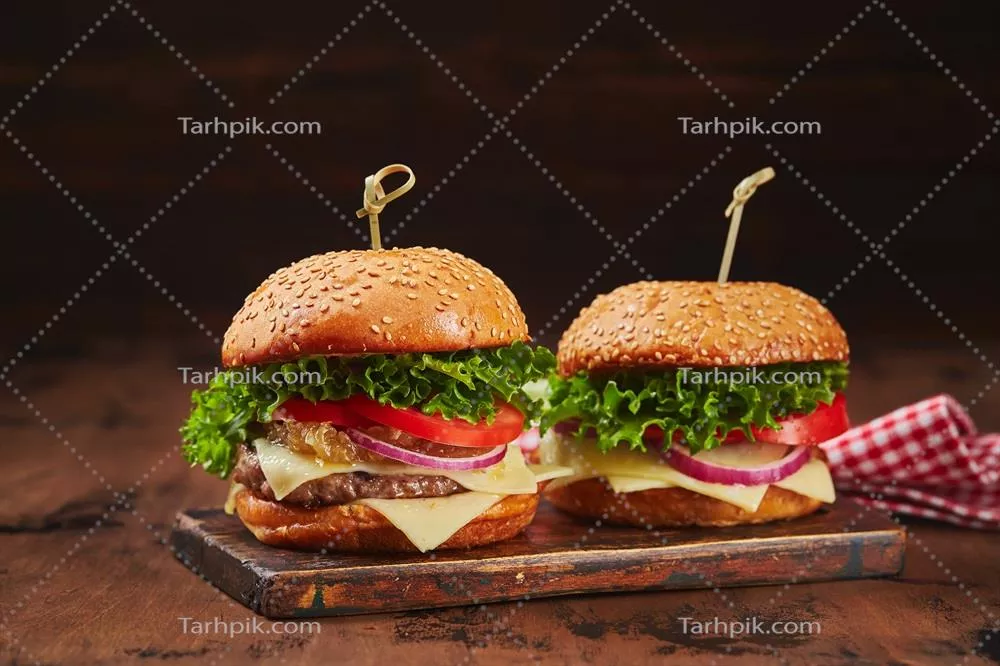 عکس دو همبرگر خانگی خوشمزه با گوشت و پنیر و مارمالاد پیاز روی تخته چوبی