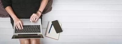 عکس تصویری از یک زن جوان آسیایی در حال کار با لپ تاپ بر روی زمین چوبی منزل