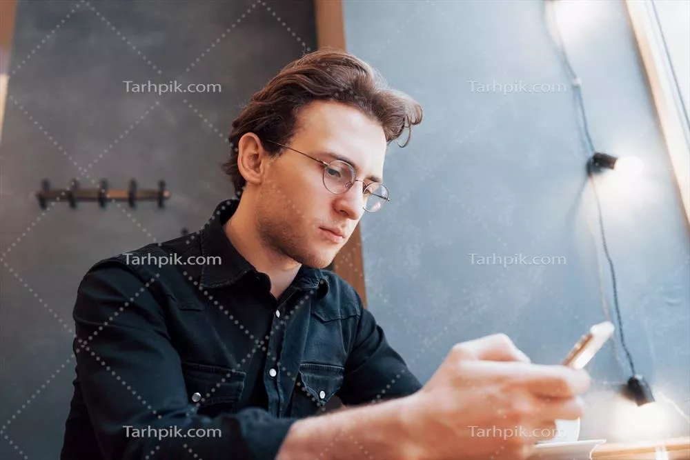 عکس مردی جذاب با ریش و هدفون در حال تماشای ویدیو در استودیوی مدرن