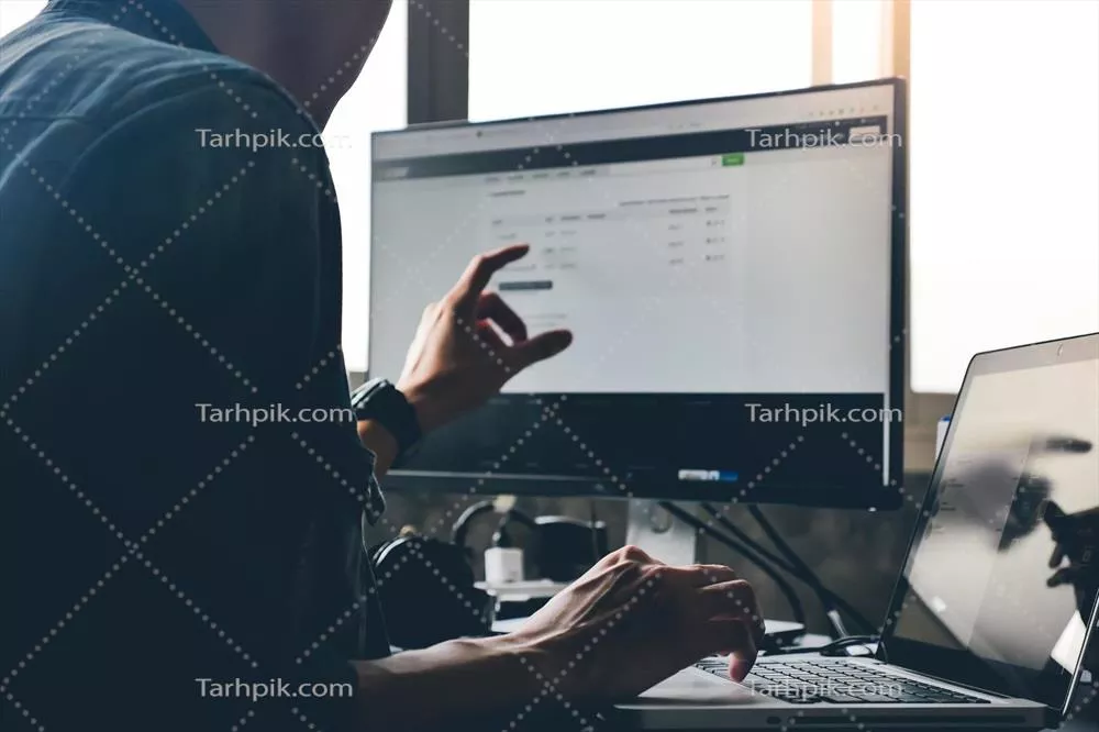 عکس مردی غیررسمی در حال استفاده از کامپیوتر روی میز کار