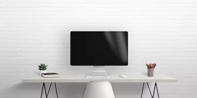 عکس تصویری از یک مانیتور کامپیوتر روی میز کار با دیوار آجری در پس زمینه