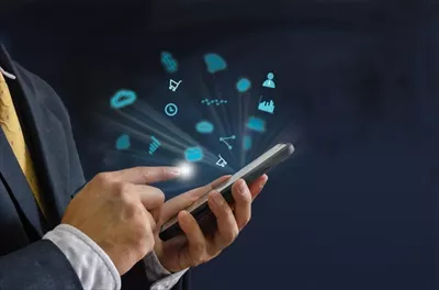 عکس دست در دست داشتن یک گوشی هوشمند با نمادهای دیجیتال متنوع