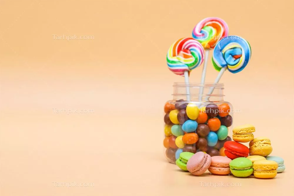 عکس مجموعه ای از شیرینی های متنوع در یک ظرف و ماکارون های فرانسوی بر روی زمینه ای کرم رنگ
