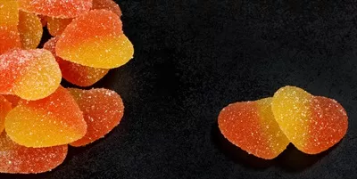 عکس دو شیرینی قلبی شکل در کنار انواع شیرینی و آبنبات های رنگارنگ