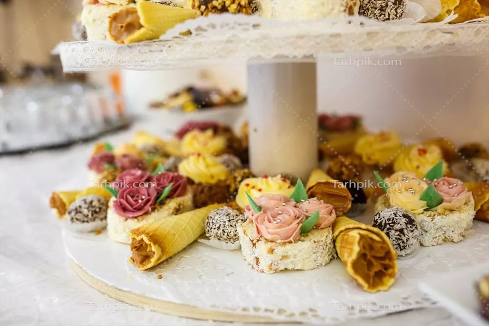 عکس نمایی زیبا از میز دسرهای جشن عروسی با تنوعی از شیرینی ها و تزئینات خاص
