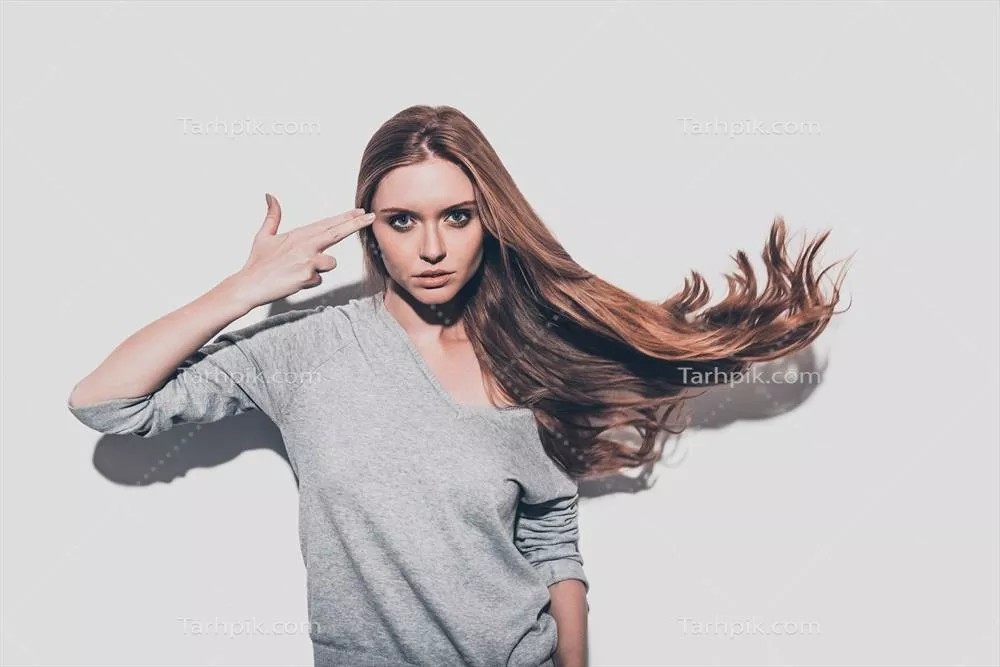 عکس زنی جوان و جذاب با موهای نامرتب در حال نشان دادن تفنگ به دوربین