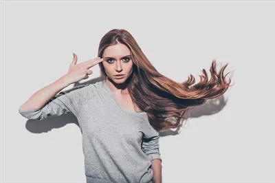 عکس زنی جوان و جذاب با موهای نامرتب در حال نشان دادن تفنگ به دوربین