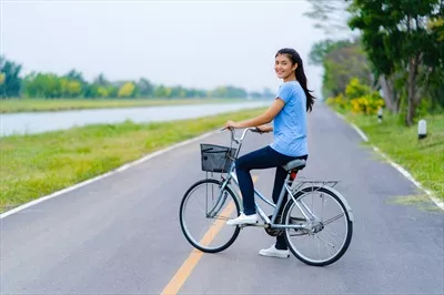 عکس زنی که در پارک با دوچرخه در حال رکاب زدن است و لحظه ای زیبا را رقم می زند