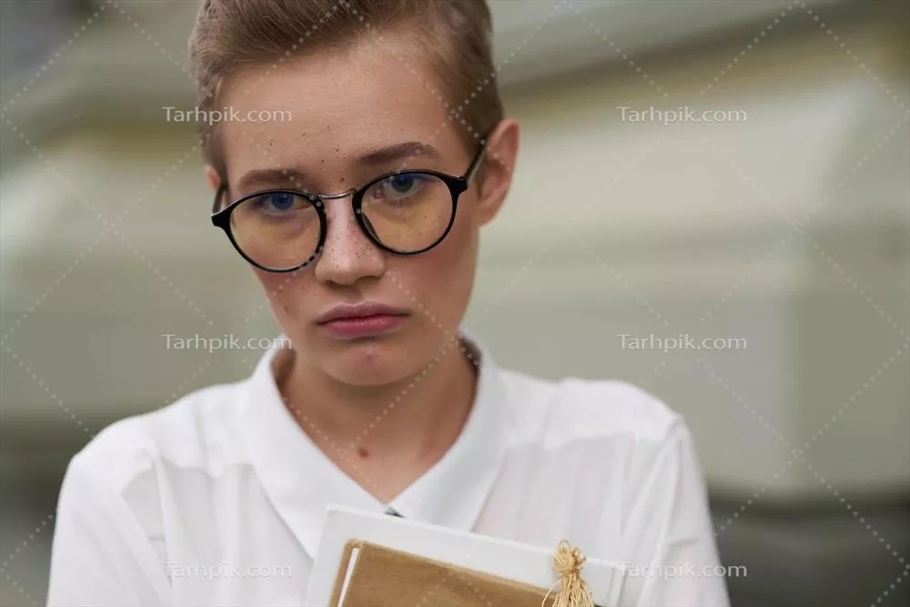 عکس دانشجویی با عینک در حال قدم زدن در شهر و مطالعه کتاب