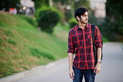 عکس دانشجوی جوان هندی با پیراهن چهارخانه قرمز و کوله پشتی در خیابان