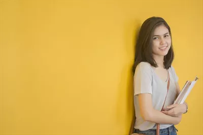 عکس پرتره ای از یک دانشجوی آسیایی در محوطه دانشگاه با حال و هوای علمی