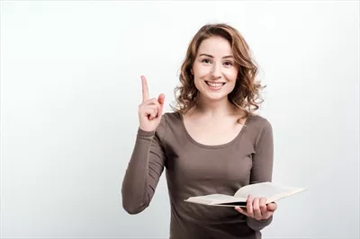 عکس دختر با کتاب در دستانش، انگشت شستش را بالا برد و راه حلی یافت