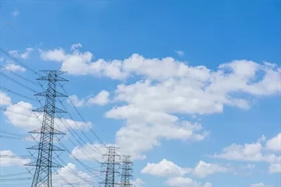 عکس تصویری از دکل برق فشار قوی در دل طبیعت با آسمان آبی