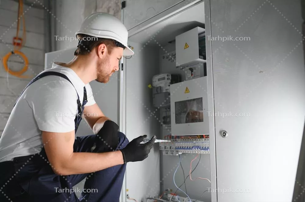 عکس برقکار مرد در حال کار بر روی تابلو برق و اتصالات الکتریکی