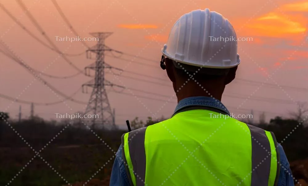 عکس نمایی از یک مهندس با کلاه ایمنی در برابر تیرک برق در غروب
