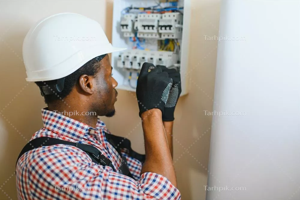 عکس برقکار مرد در حال کار بر روی تابلو برق و اتصالات الکتریکی